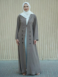 Woman wearing a long light brown coat over a white dress with a beige background