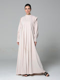 Woman wearing a light pink abaya on a gray background