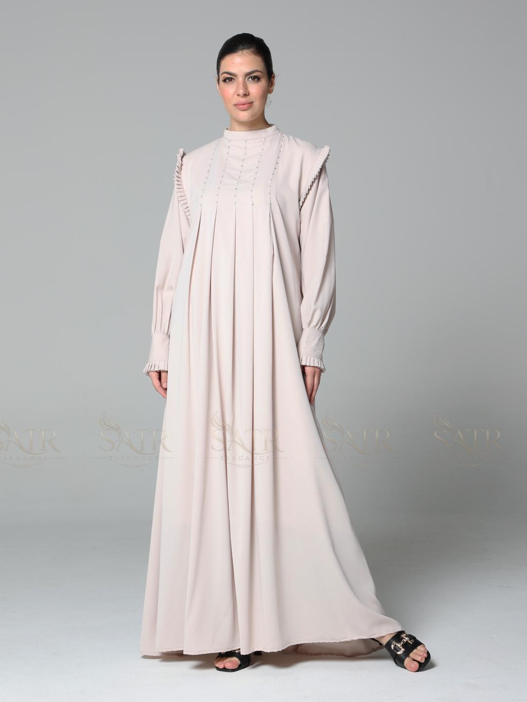 Woman wearing a light pink abaya on a gray background