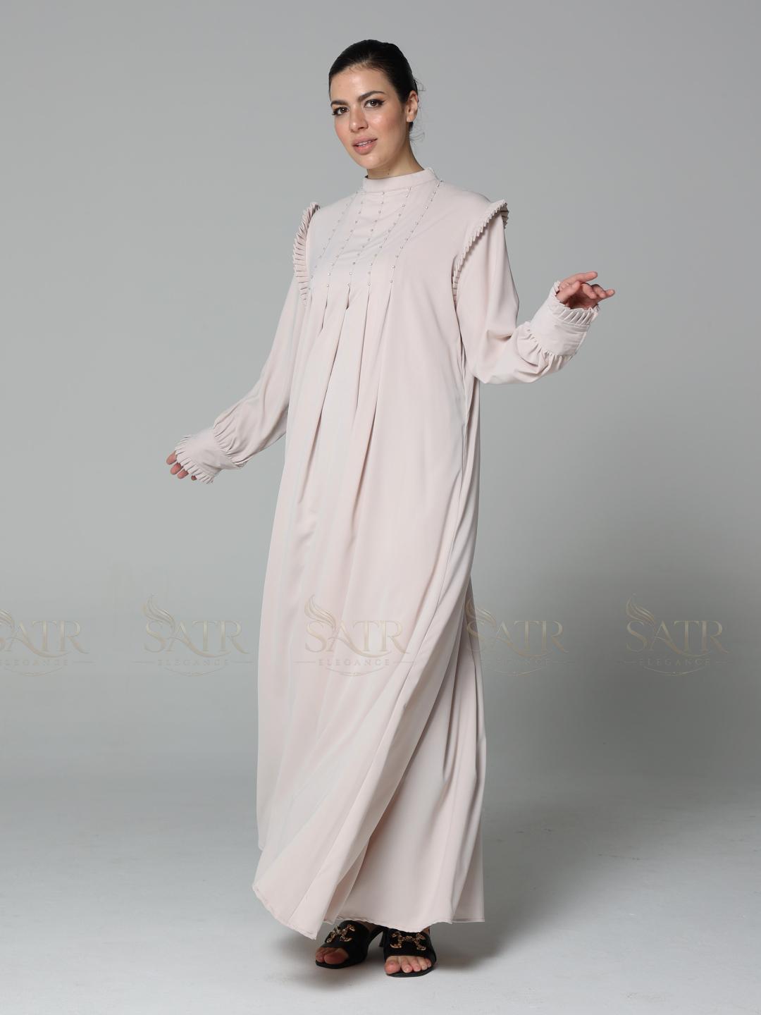 Woman wearing a light pink dress with lace details on a gray background