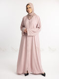 Woman wearing a light pink abaya with a matching hijab on a white background