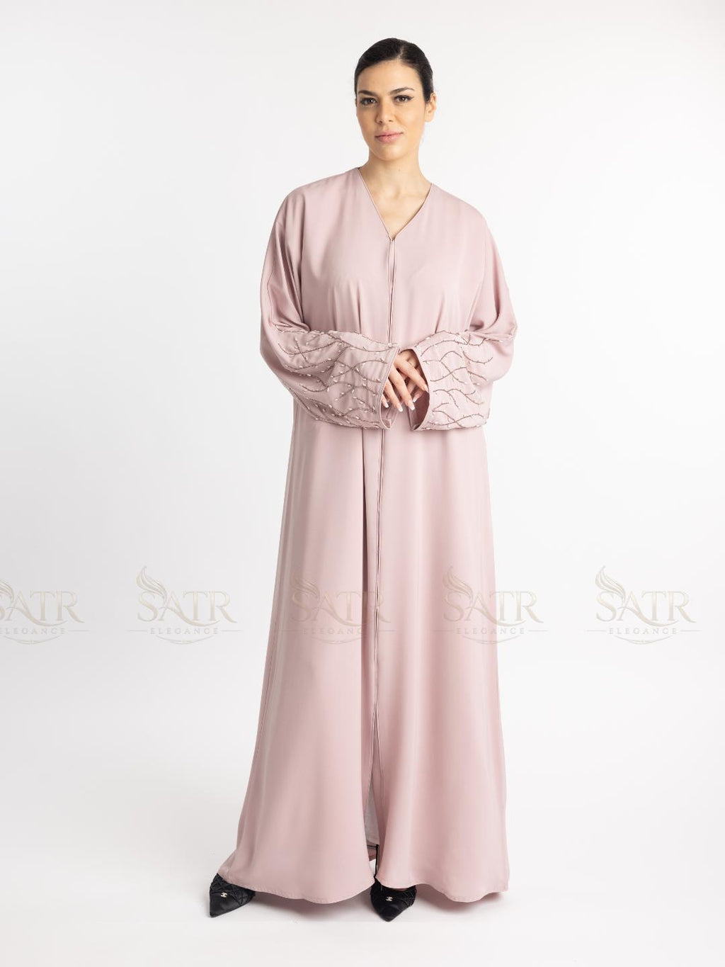 Woman wearing a pink abaya with lace sleeves on a white background