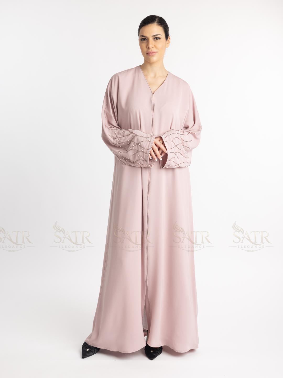 Woman wearing a pink abaya with lace sleeves on a white background