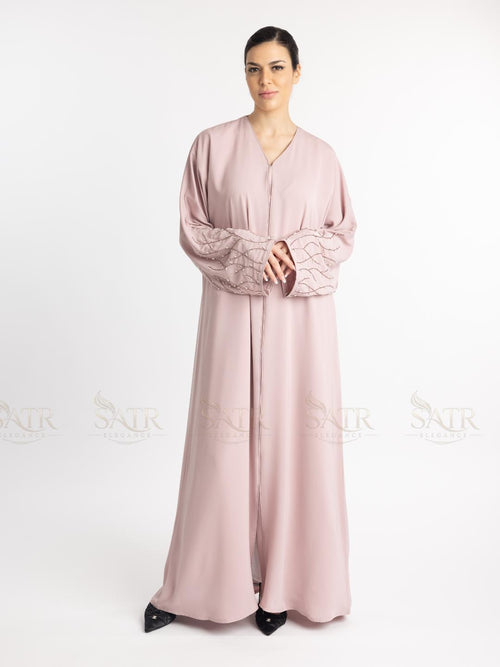 Woman wearing a pink abaya with lace sleeves on a white background