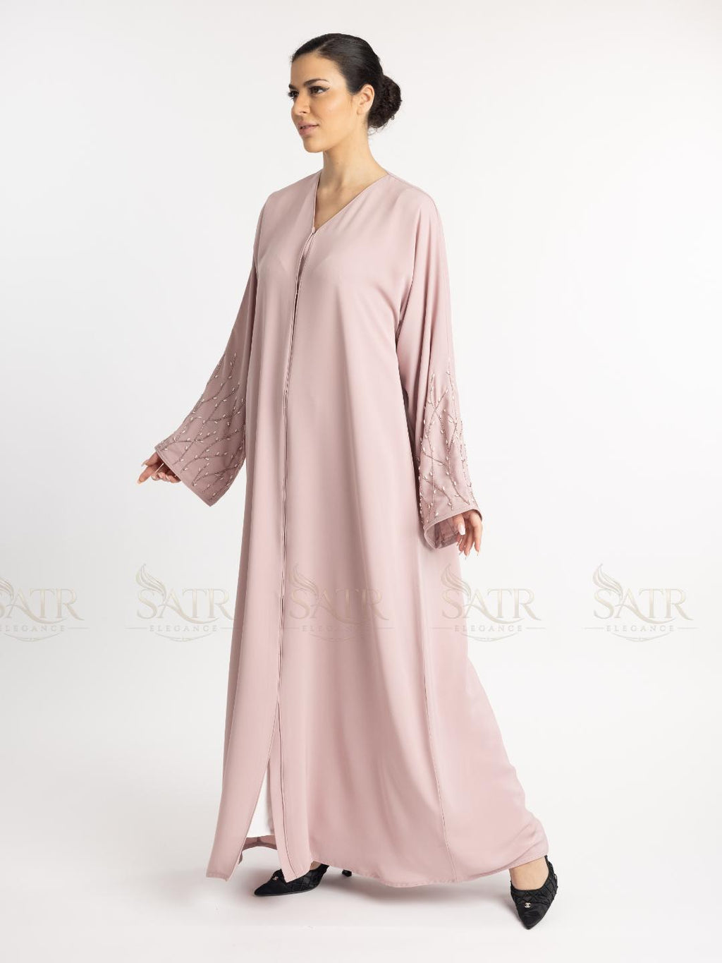 Woman wearing a light pink abaya on a white background