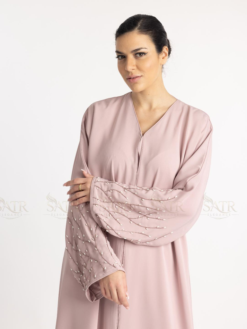 Woman wearing a light pink dress with a textured sleeve on a white background