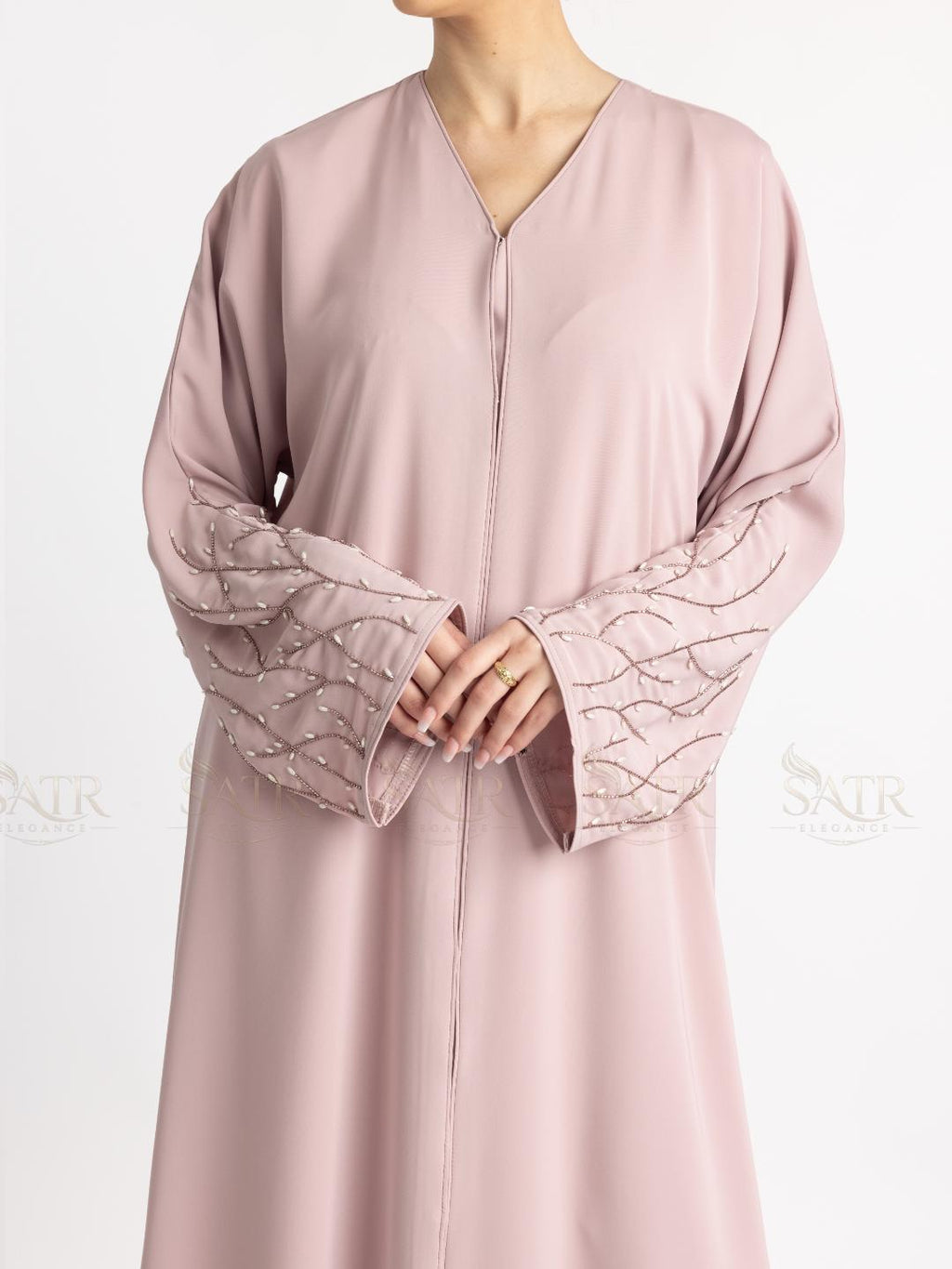 Pink abaya with intricate detailing on cuffs against a white background