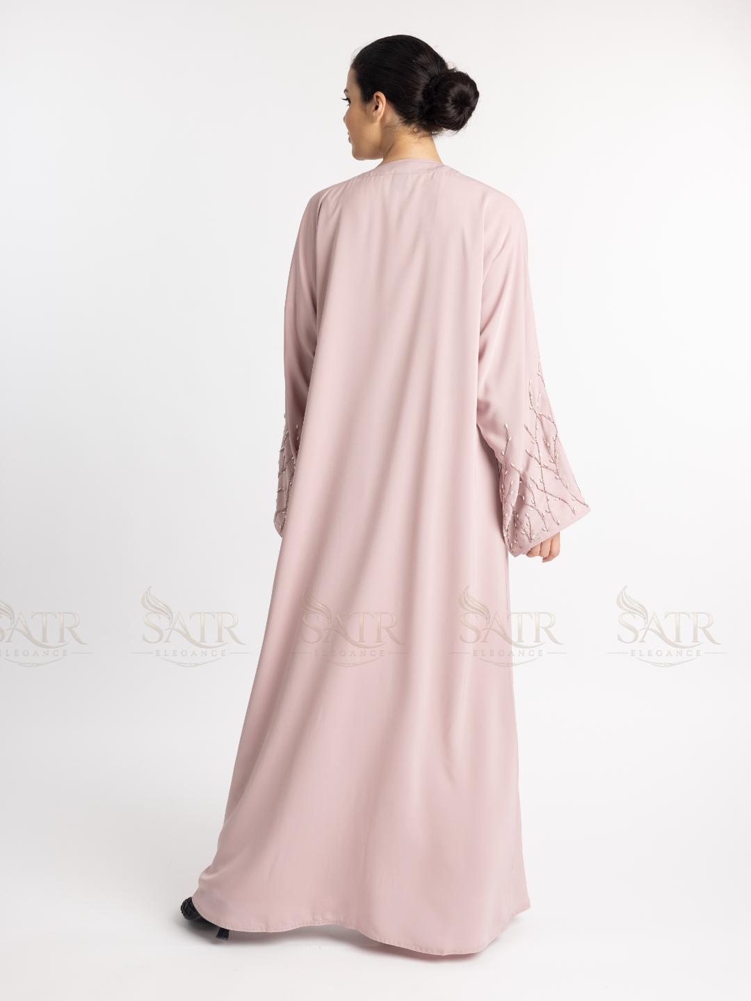 Woman wearing a light pink abaya on a white background