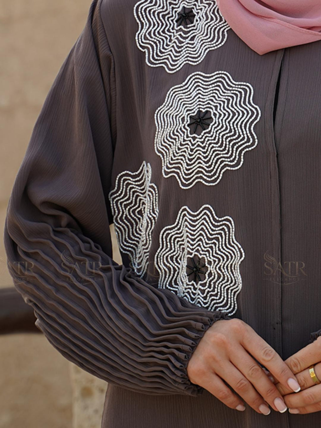Brown garment with white floral patterns and a pink hijab, brand 'Satr' visible.