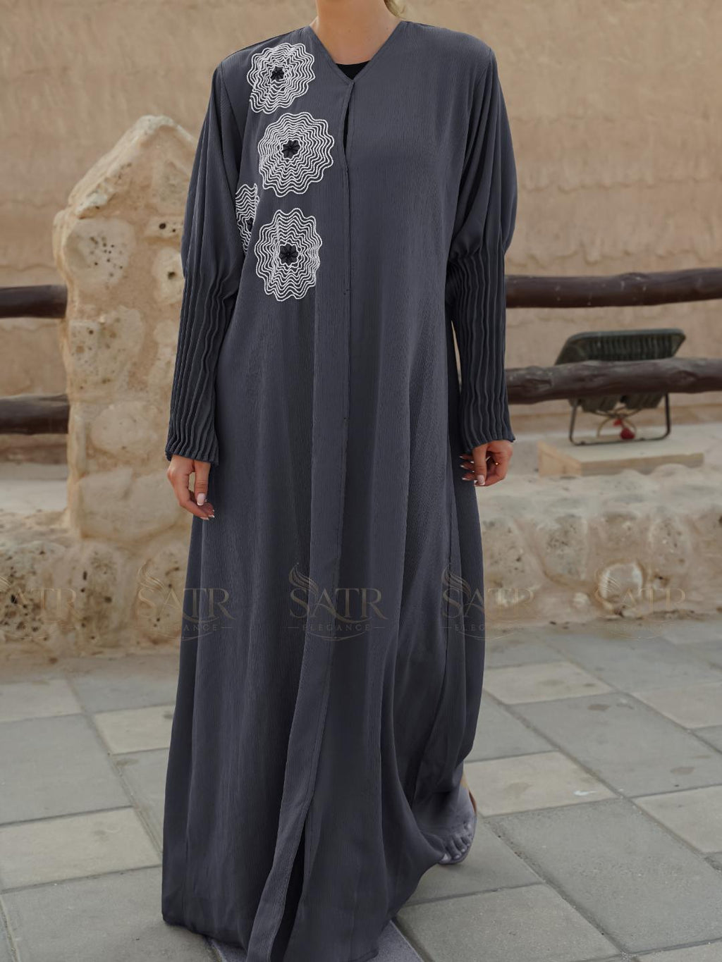 Long dark gray dress with floral embroidery on a stone pavement background