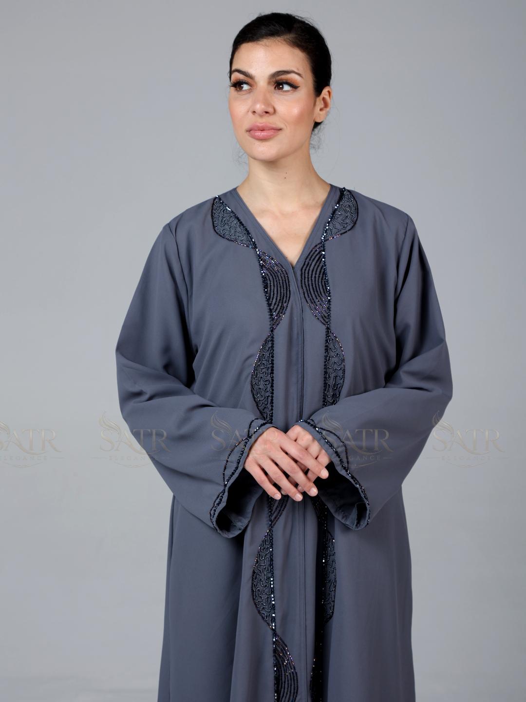 Woman wearing a gray abaya with black embroidery on a gray background