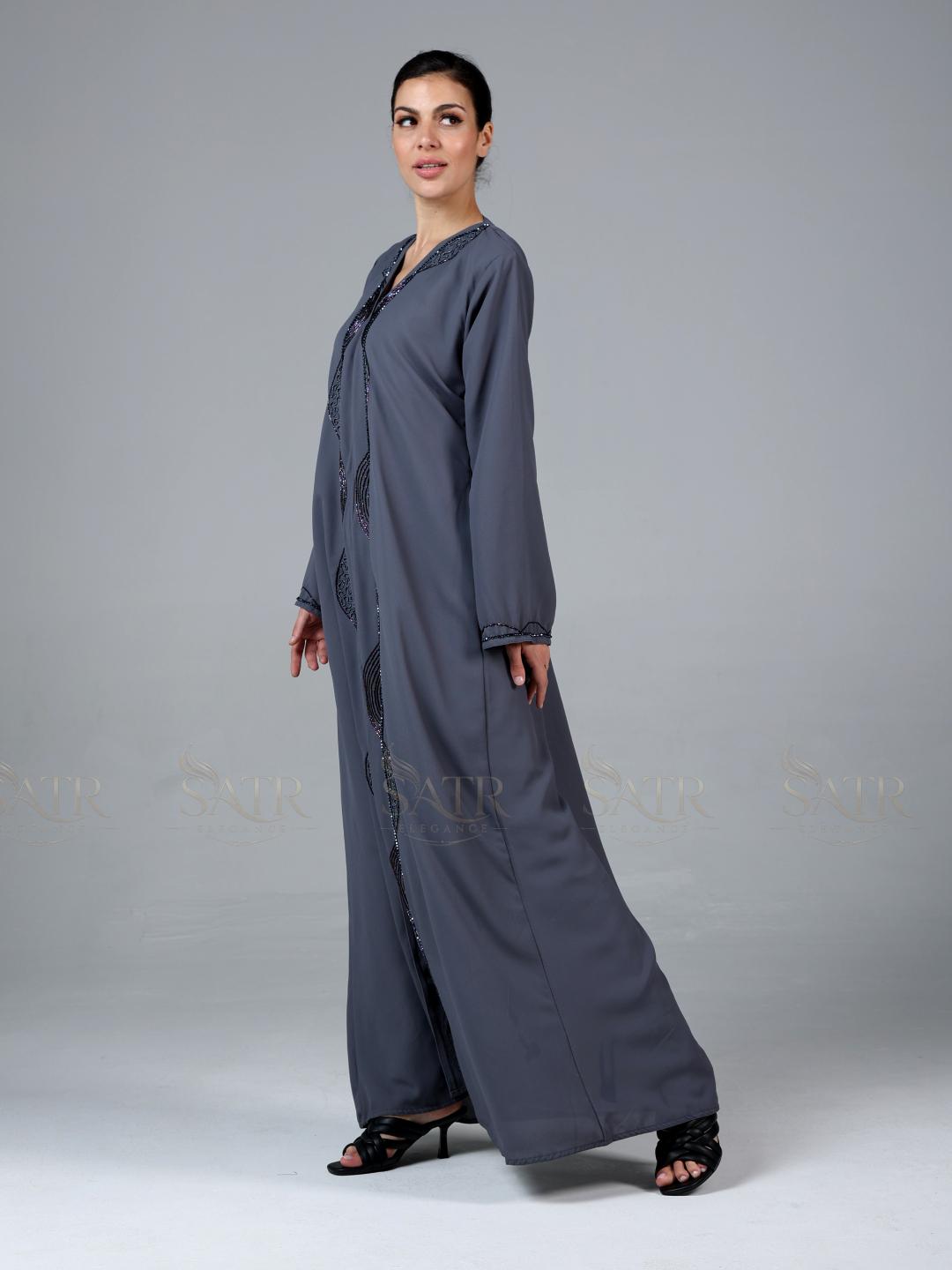 Woman wearing a long gray dress with a plain background