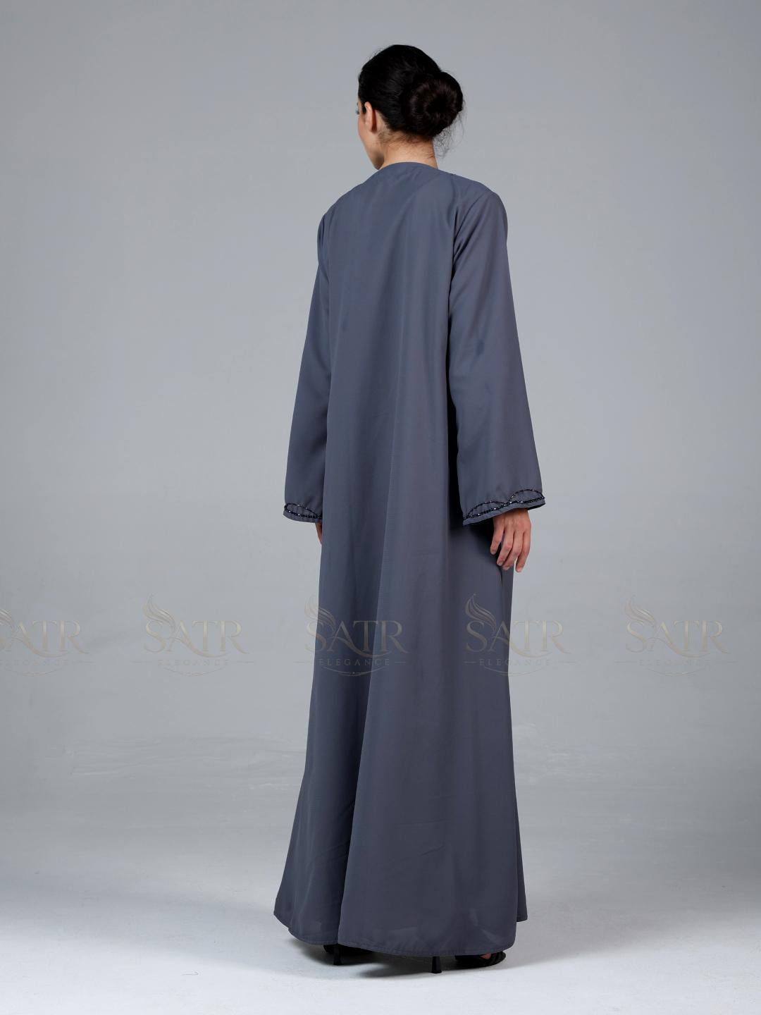 Person wearing a long gray dress against a plain background