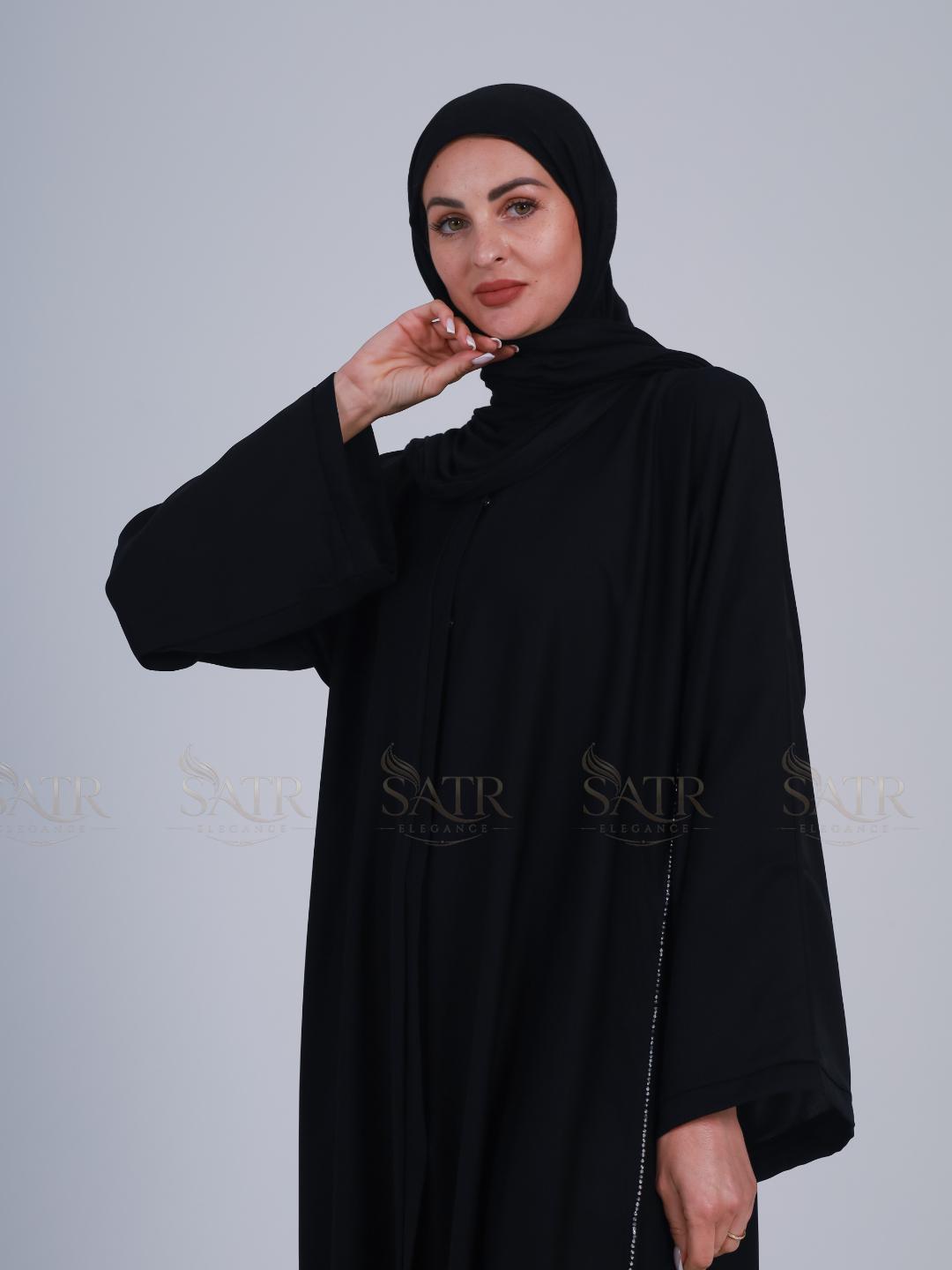 Woman wearing a black abaya and hijab against a light gray background