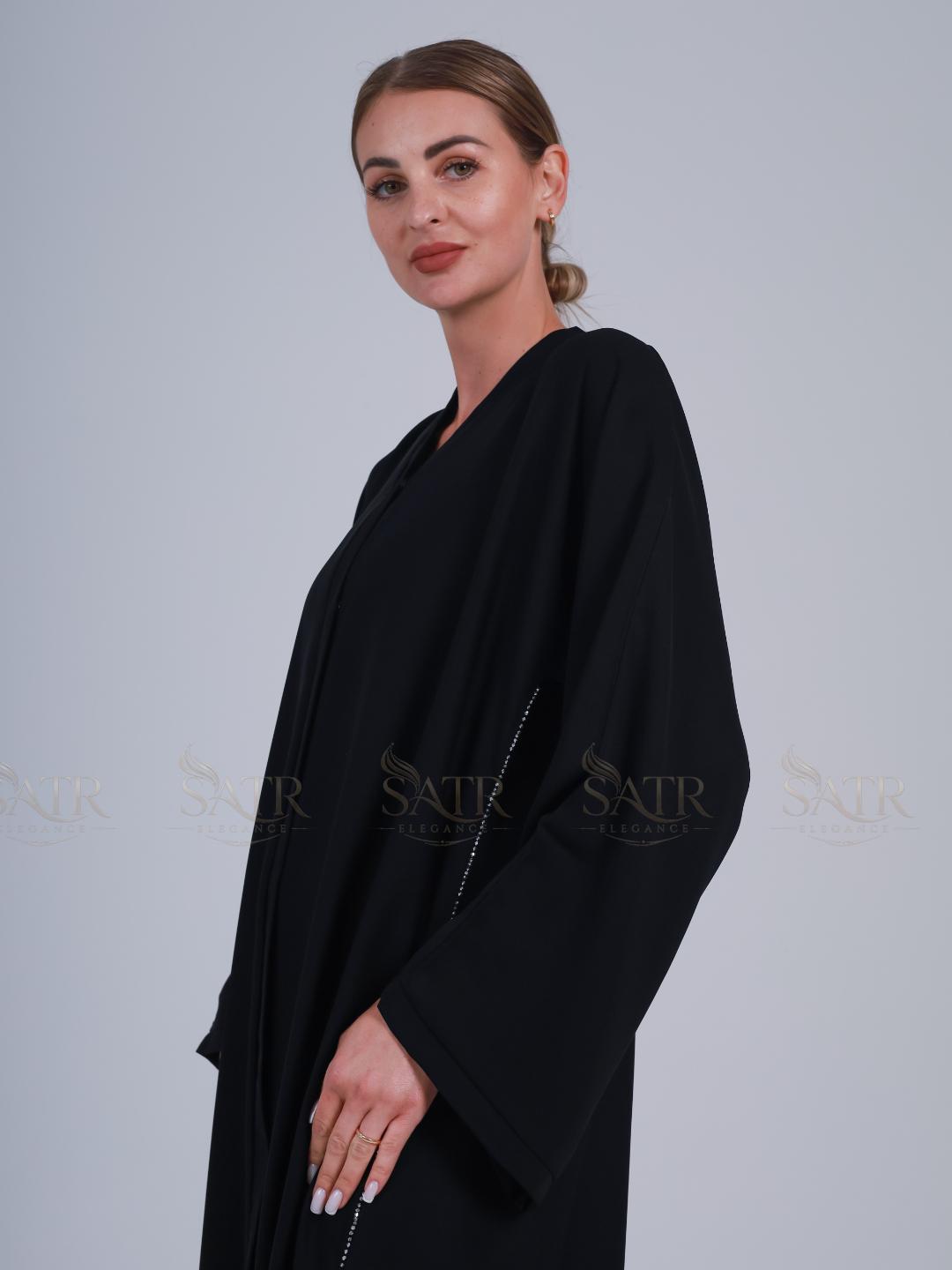 Woman wearing a black abaya against a plain background