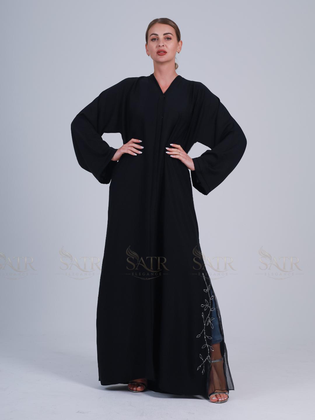 Woman wearing a black abaya with embroidery on a gray background