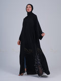 Woman wearing a black abaya with intricate detailing on a white background