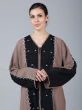 Woman wearing a black and brown outfit with intricate detailing on a gray background