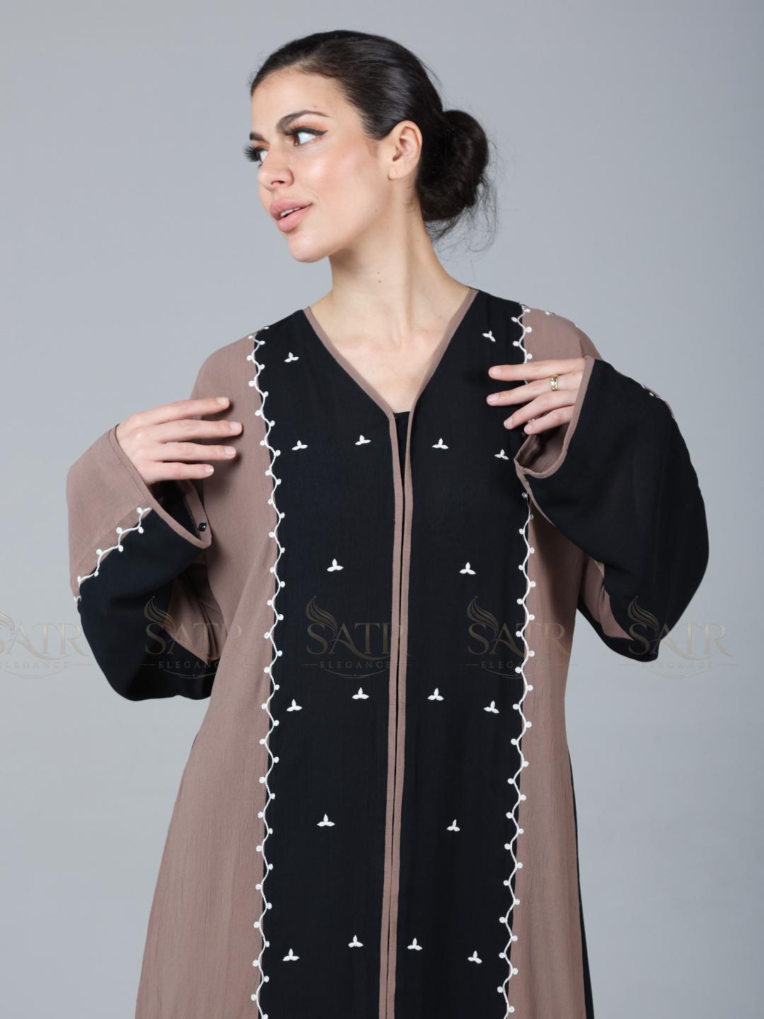 Woman wearing a black and brown dress with intricate detailing on a gray background