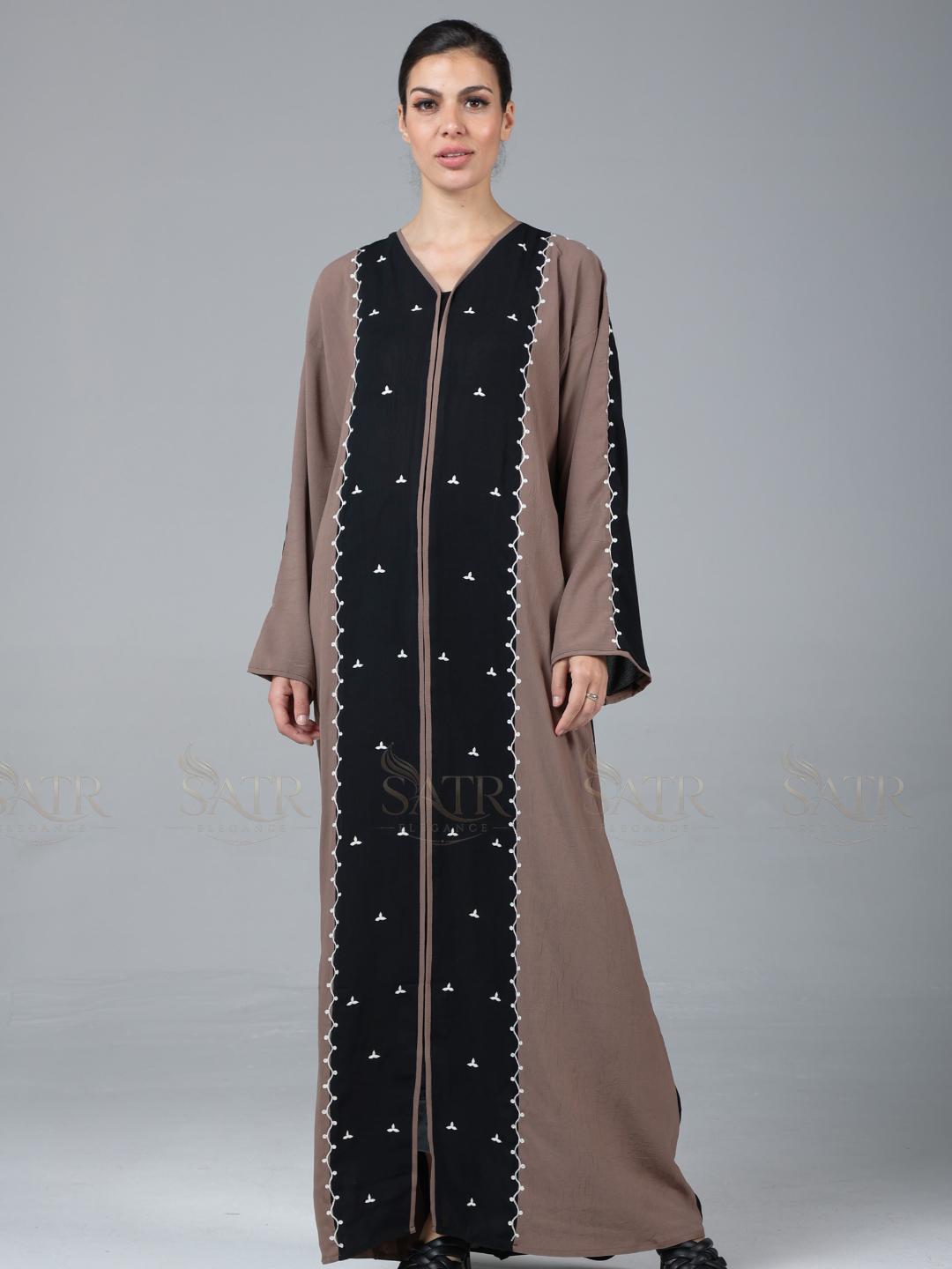 Woman wearing a long, brown and black dress with star patterns on a gray background