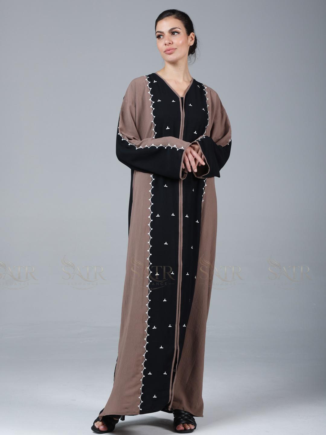 Woman wearing a long, brown and black dress with star patterns on a gray background