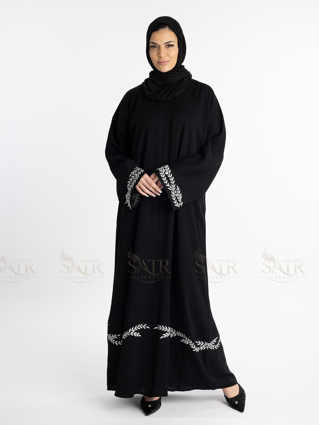 Classy woman wearing a black luxury abaya with white embroidery on a white background