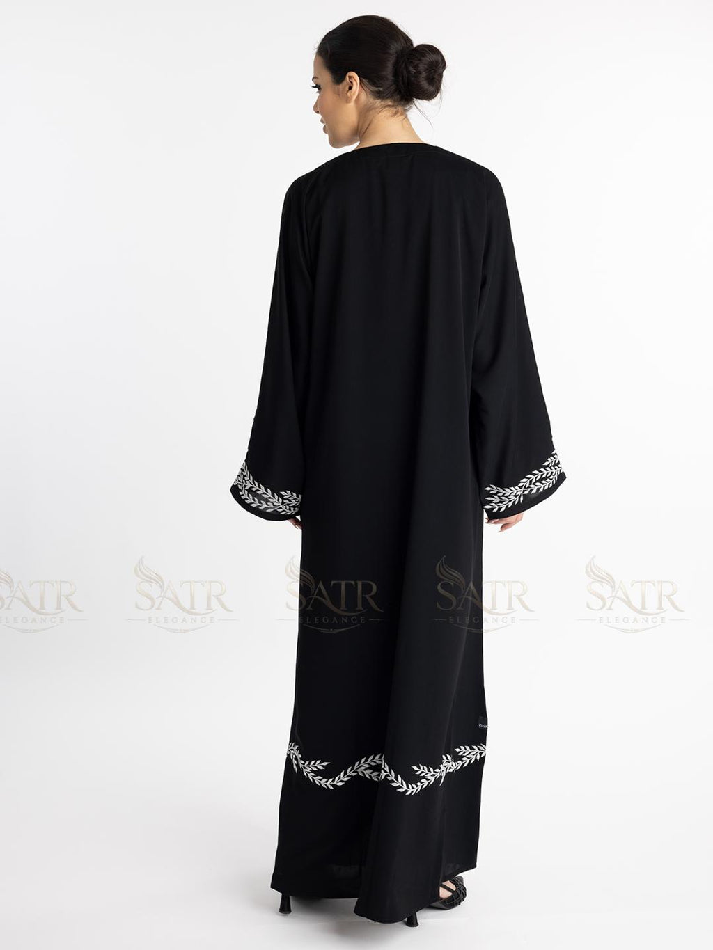 Premium black abaya with white embroidery on a white background show-casing embroidery on sleeves and back bottom.