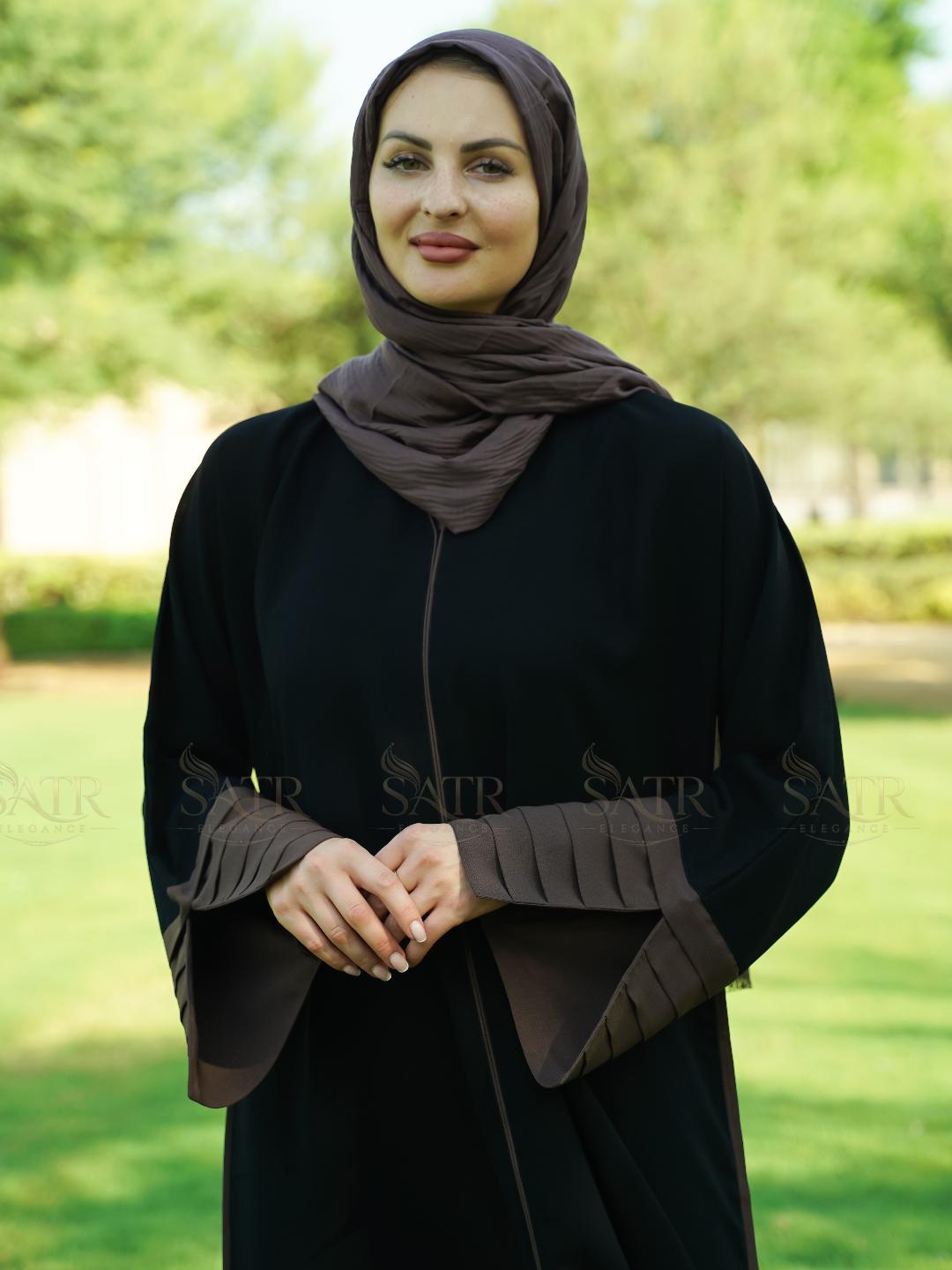 Woman wearing a black abaya with a brown hijab in an outdoor setting