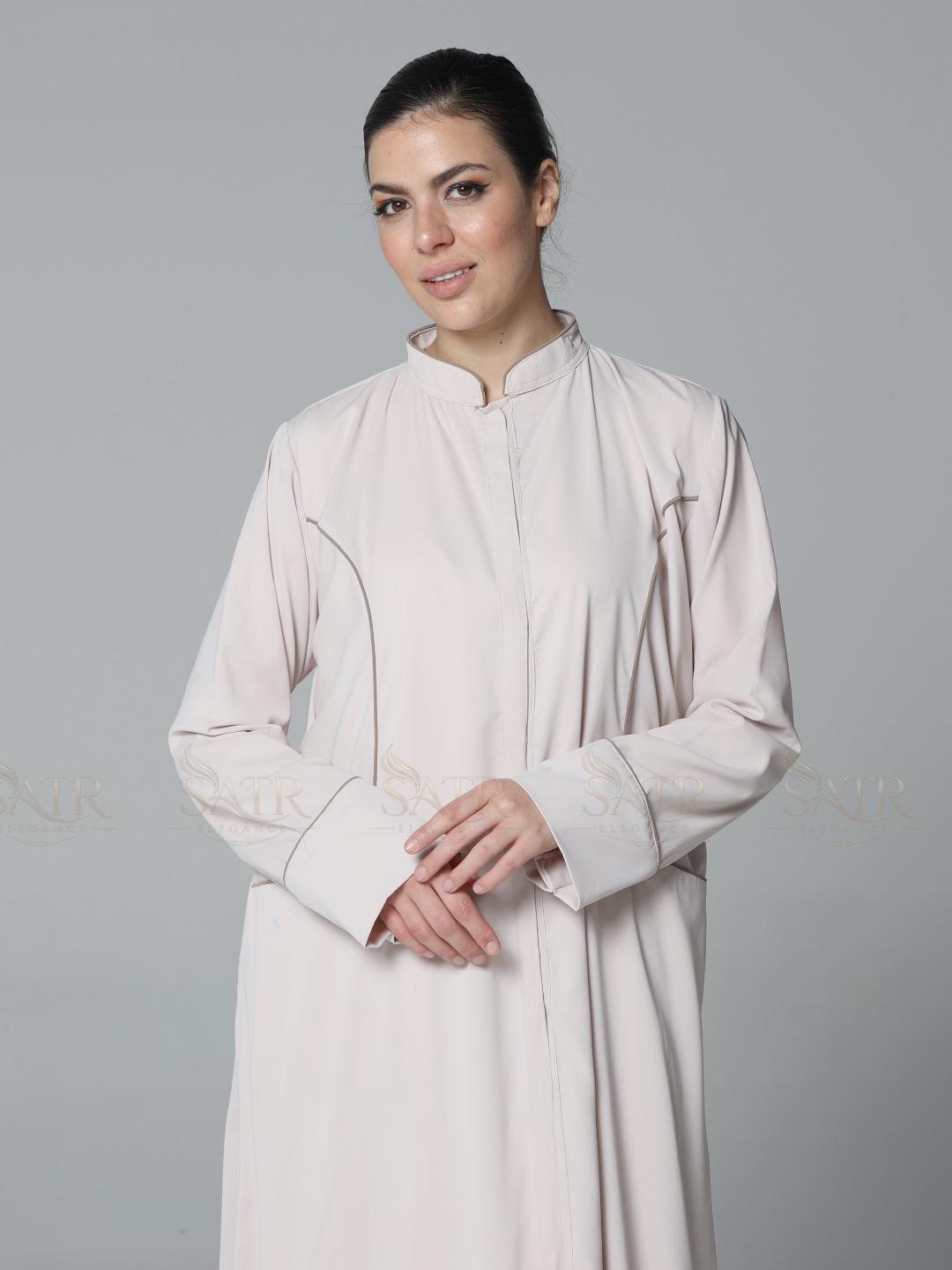 Woman wearing a light-colored traditional outfit against a gray background
