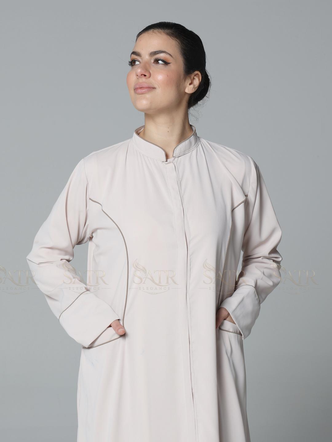 Woman wearing a light-colored long coat against a gray background