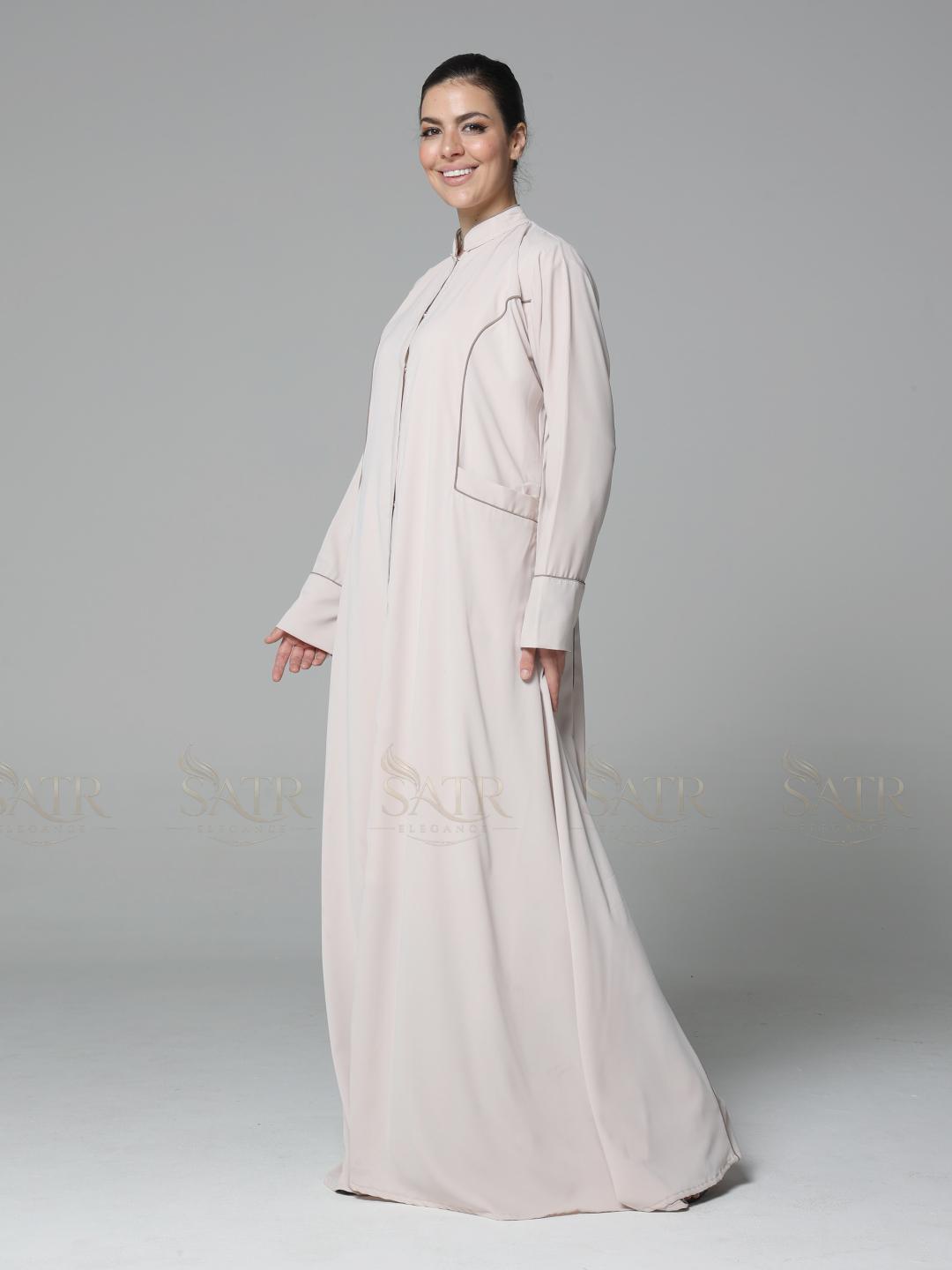 Woman wearing a light pink abaya on a gray background