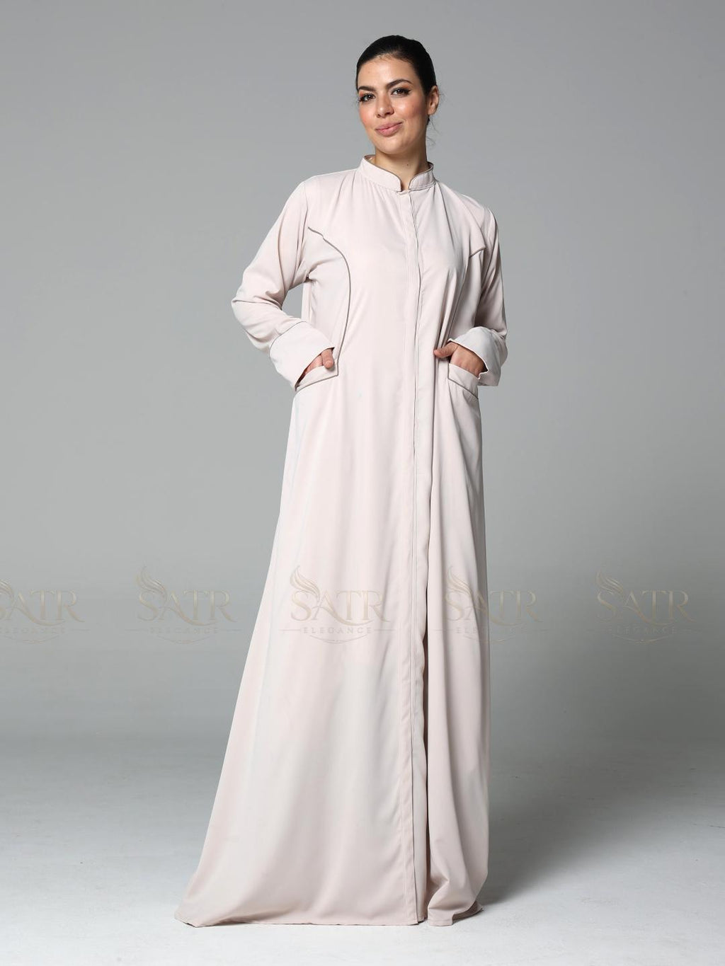 Woman wearing a light pink abaya on a gray background