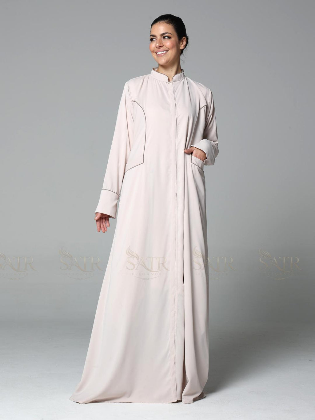 Woman wearing a light pink abaya on a gray background