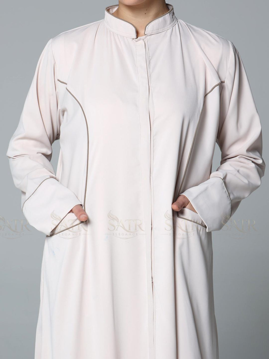 Person wearing a light pink abaya with a plain background