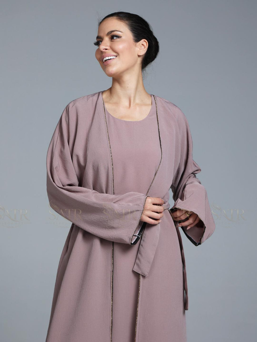 Women wearing pink abaya with small work on front pattern and grey background.