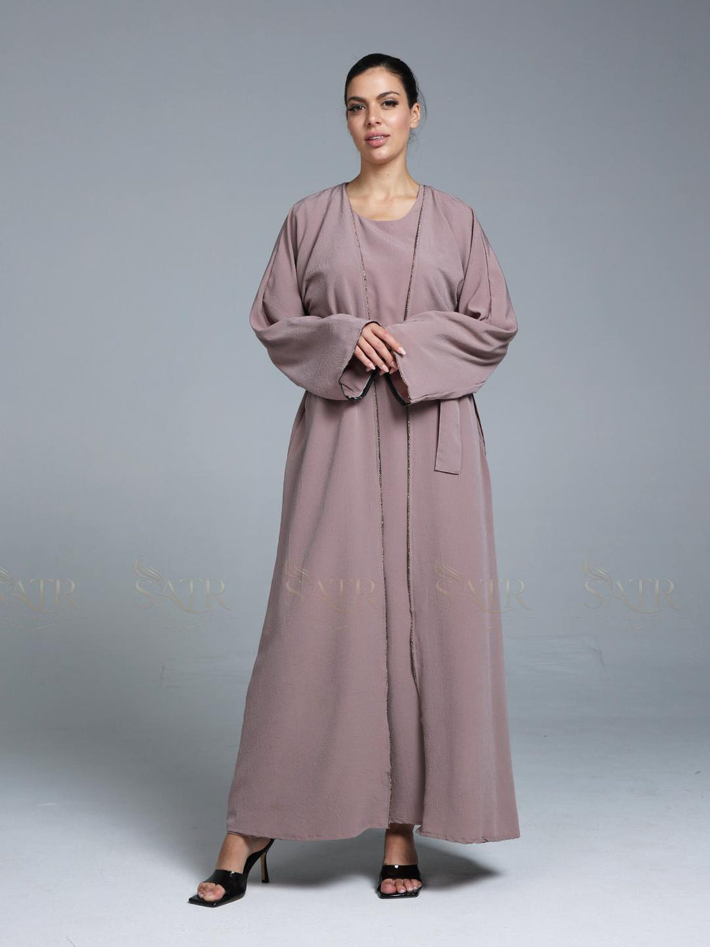 Women wearing pink abaya with small work on front pattern and grey background.