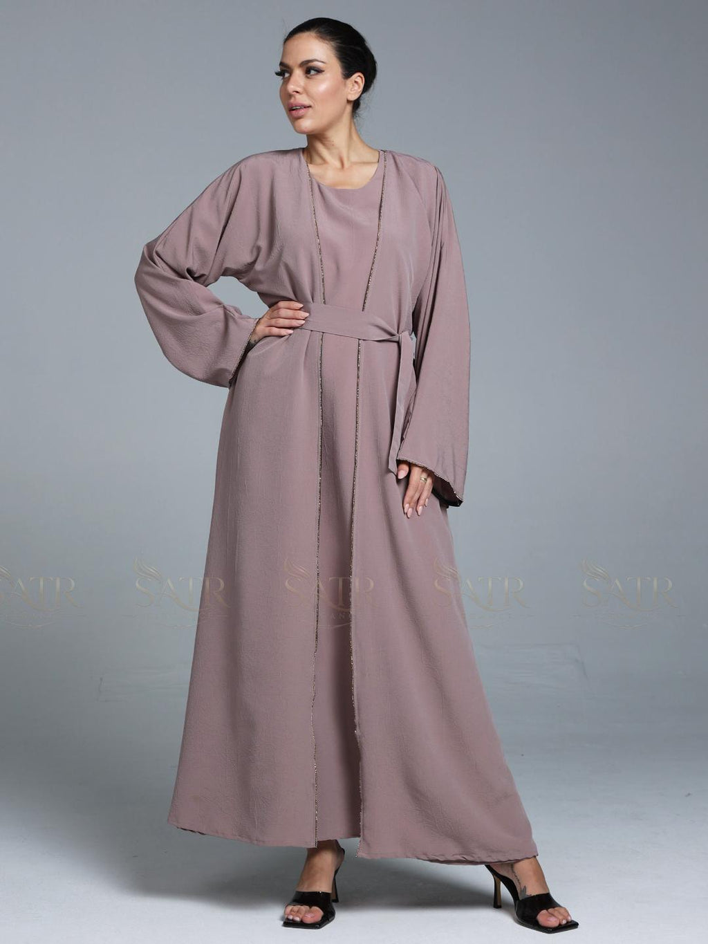 Women wearing pink abaya with small work on front pattern and grey background.