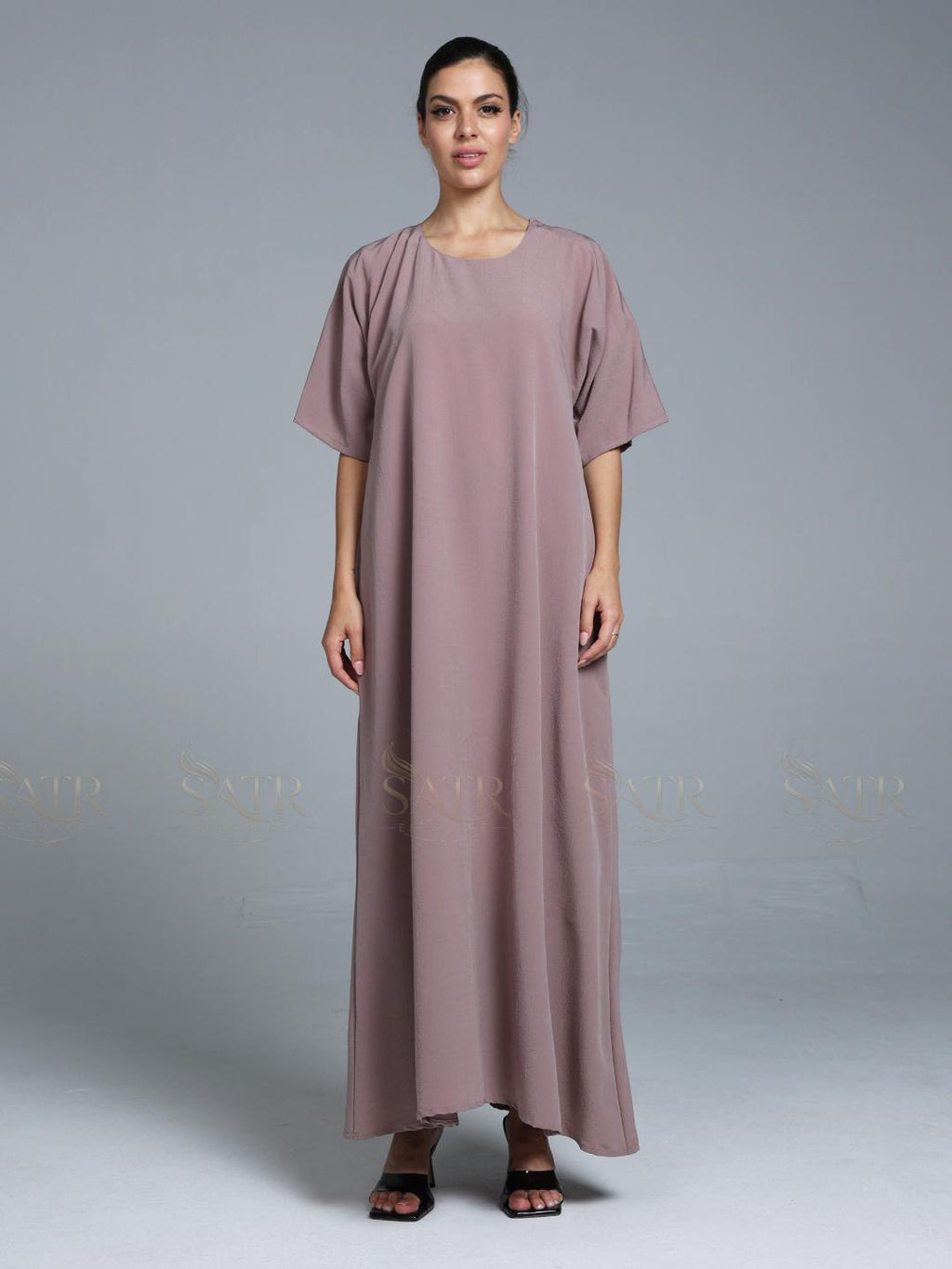 Women wearing pink abaya with small work on front pattern and grey background.