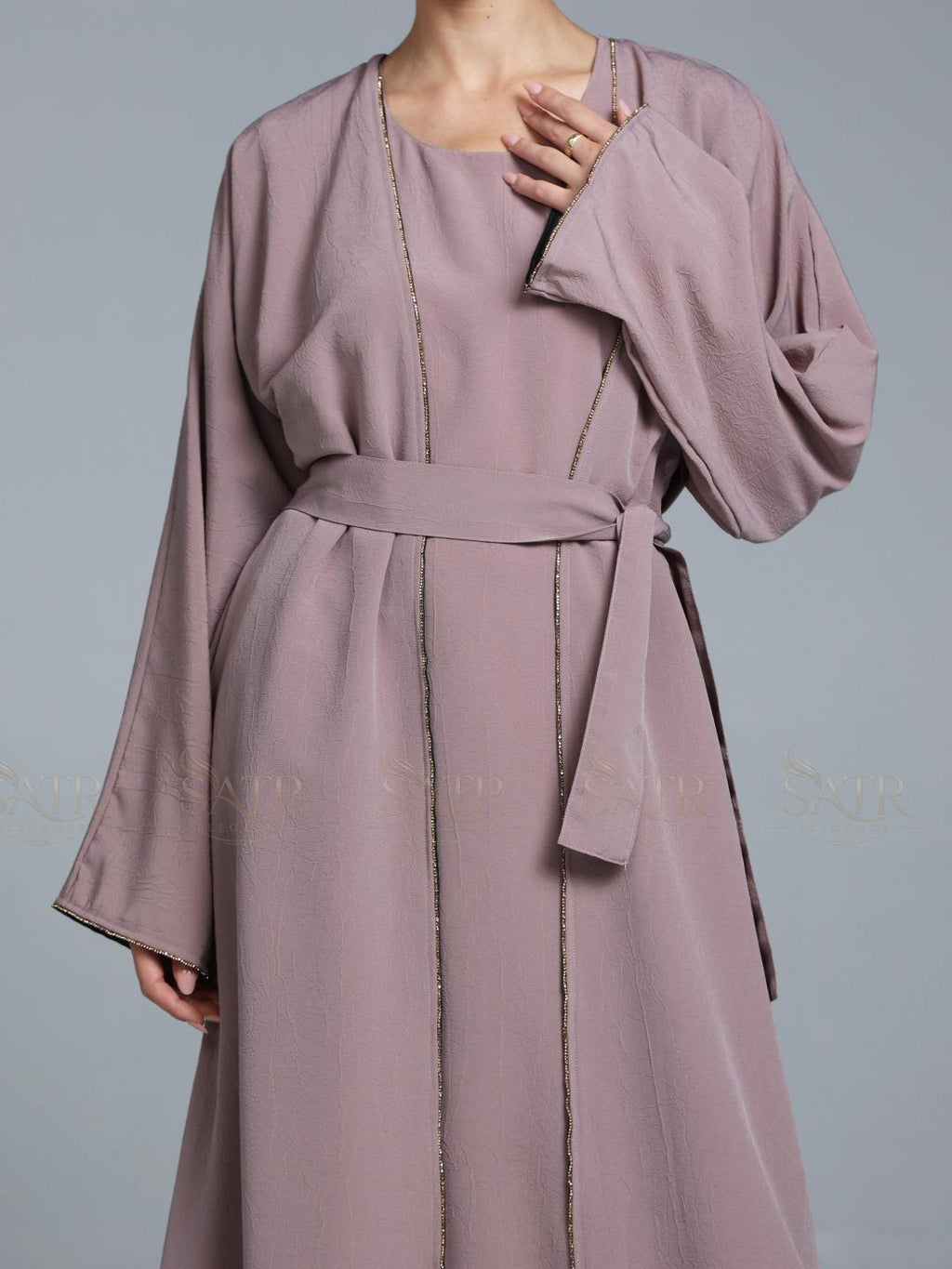 Women wearing pink abaya with small work on front pattern and grey background.